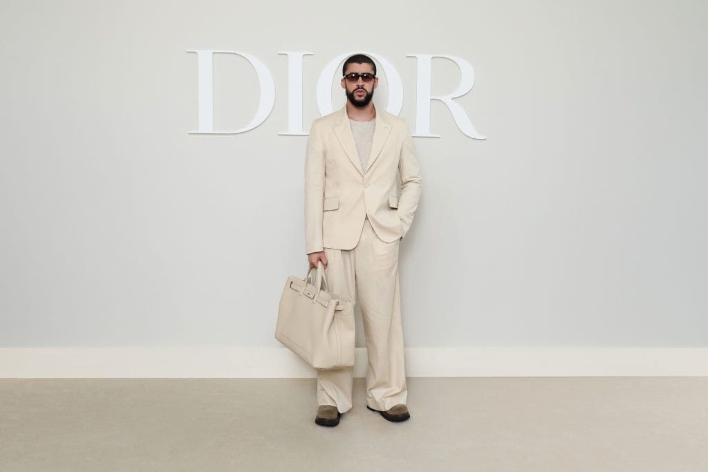 Bad Bunny sorprende con un atuendo monocromático color hueso. Lleva traje sastre, un bolso en el mismo color y gafas oscuras que elevan su "look". 