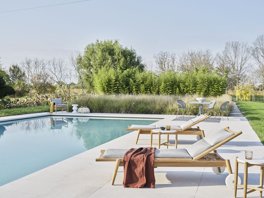 El entorno de piscina se equipa con tumbonas y una mesa con sillas donde conversar o tomar algo