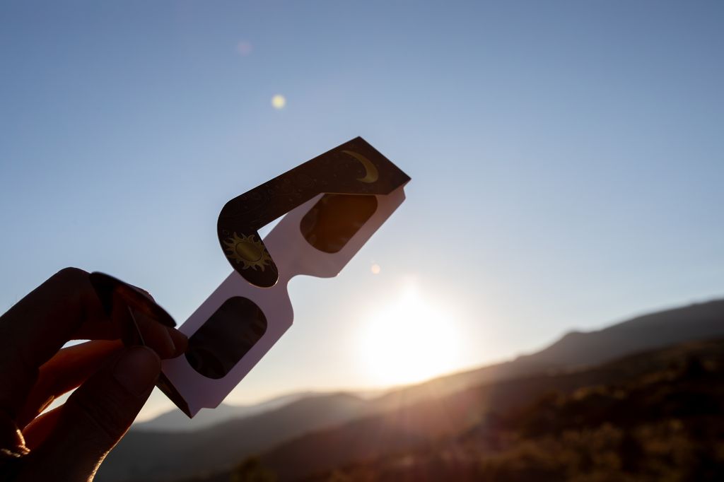 manos sujetando unas gafas homologadas para ver el eclipse solar