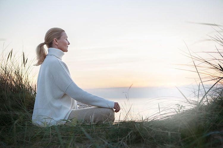 Mujer meditando a la orilla del mar