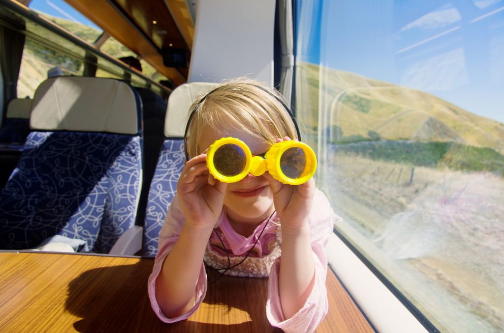 Niña en un tren con unos prismáticos