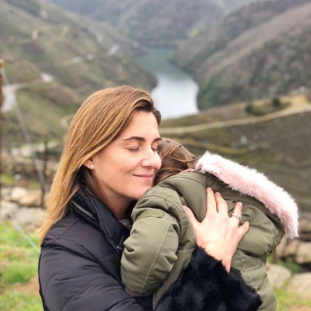Primer plano de Carlota Corredera con su hija alba en brazos y un paisaje de fondo