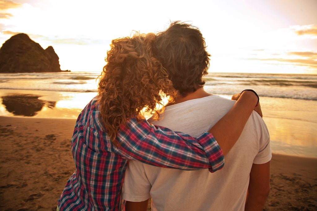 pareja mirando la puesta de sol, abrazados