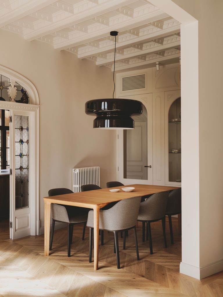 Comedor con mesa de madera, sillas grises y lámpara de techo negra