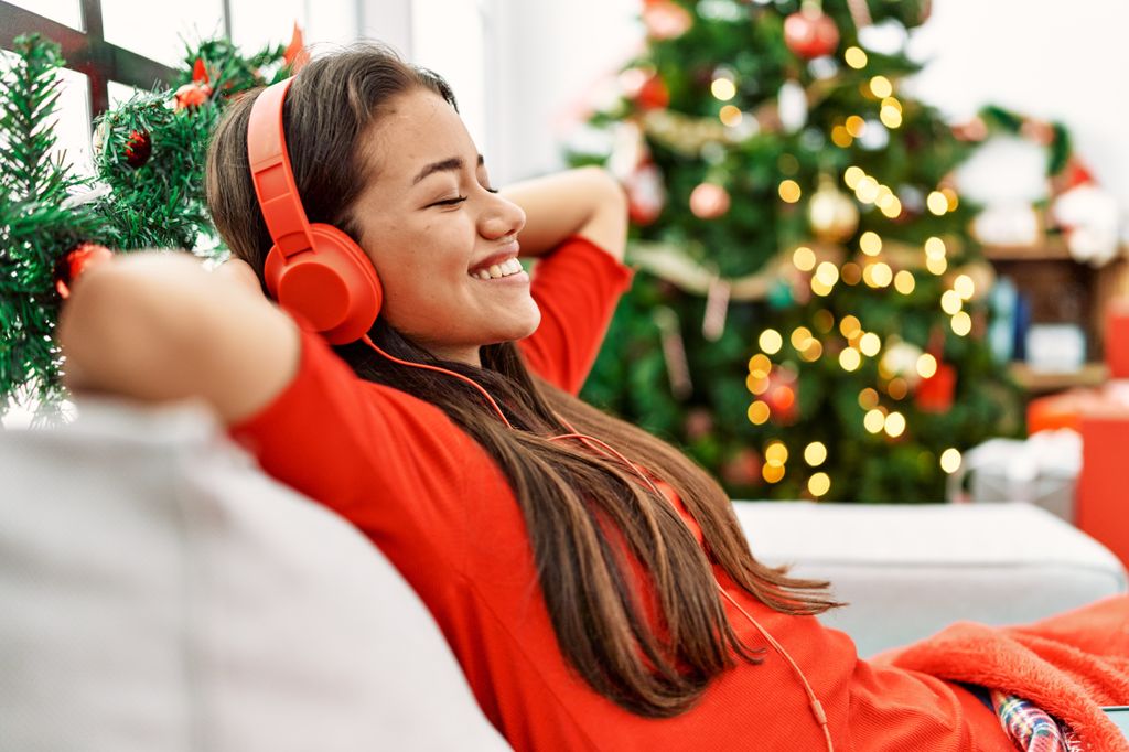 mujer escuchando música navideña junto al árbol de Navidad