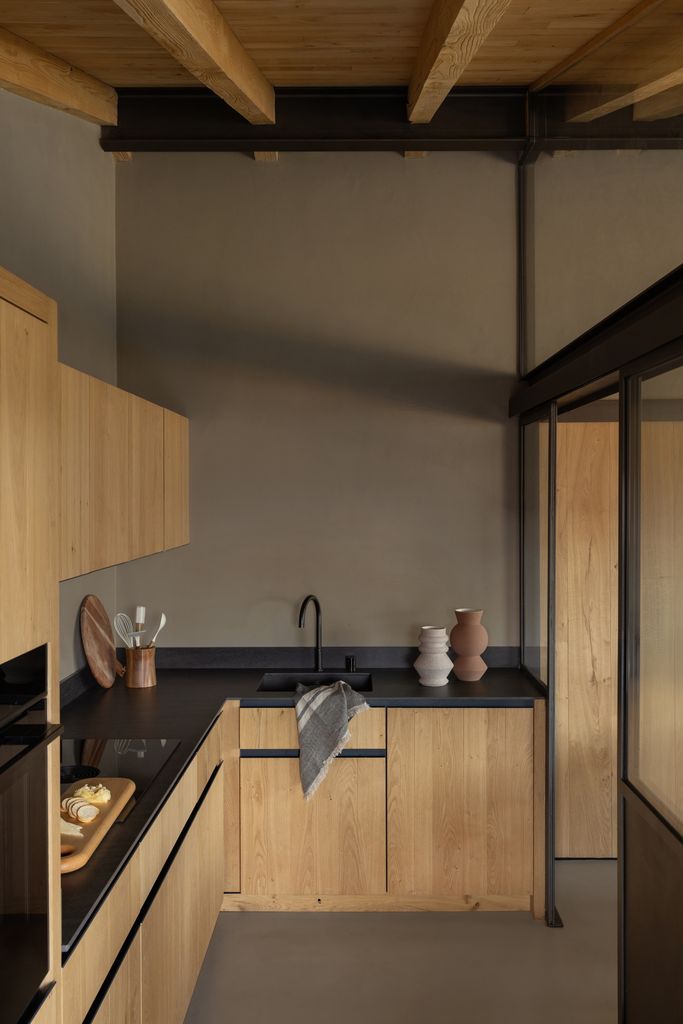Cocina con mobiliario de madera y encimeras de color negro