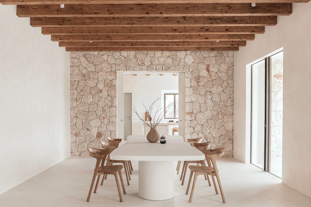Comedor con muro de piedra y techo de vigas vistas