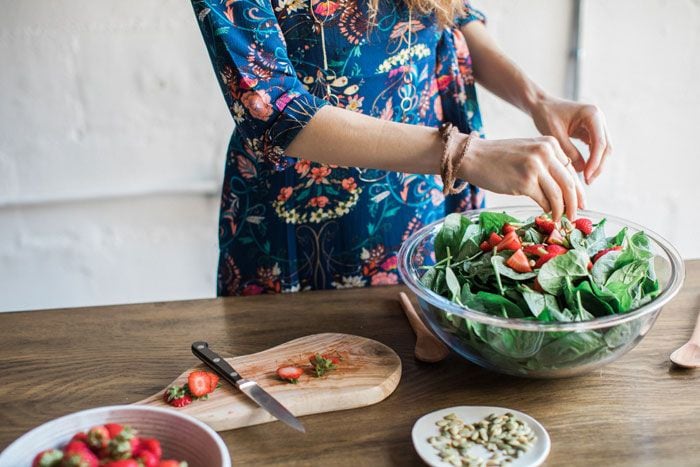 mujer preparando una ensalada con fresas