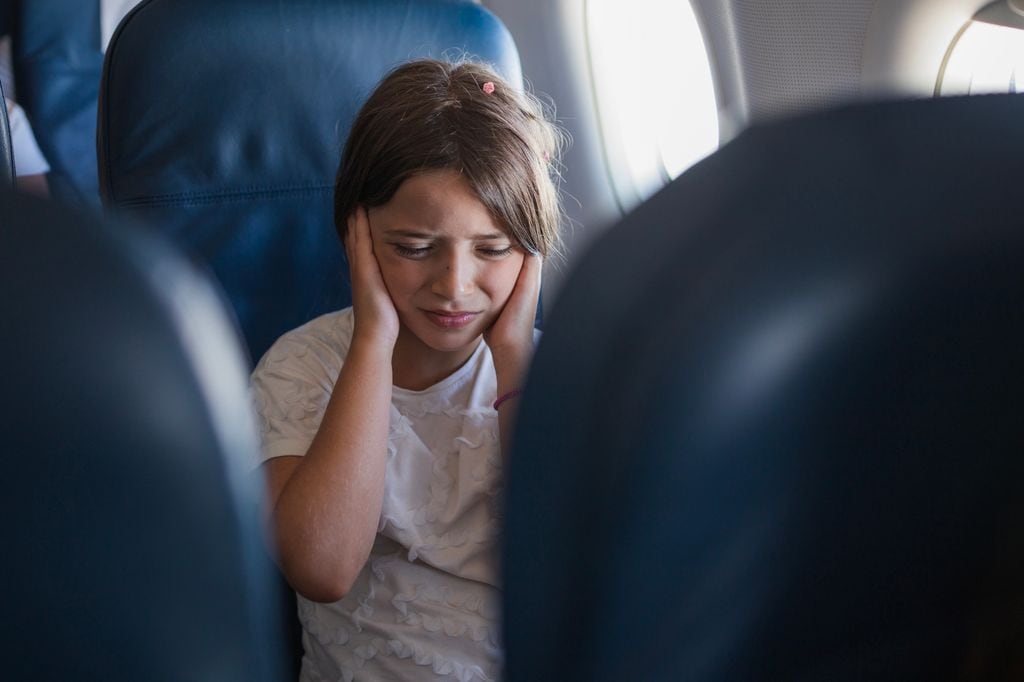 niña tapándose los oídos en un avión