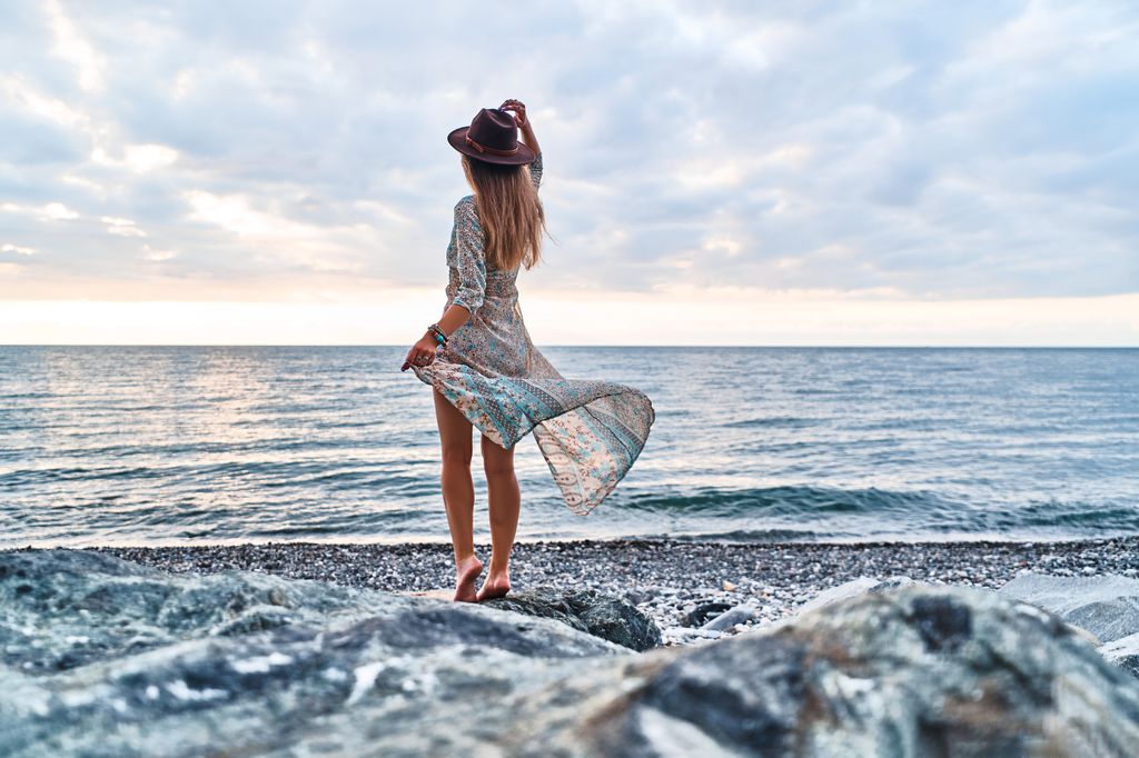 mujer relajada en la playa, descalza junto al mar