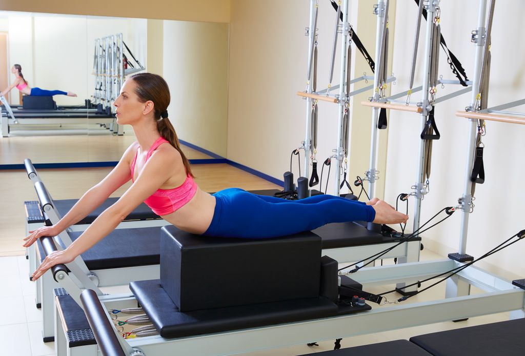 mujer joven haciendo pilates con máquinas