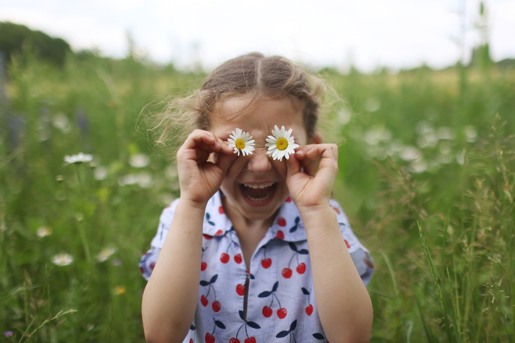 Niña al aire libre con flores en los ojos