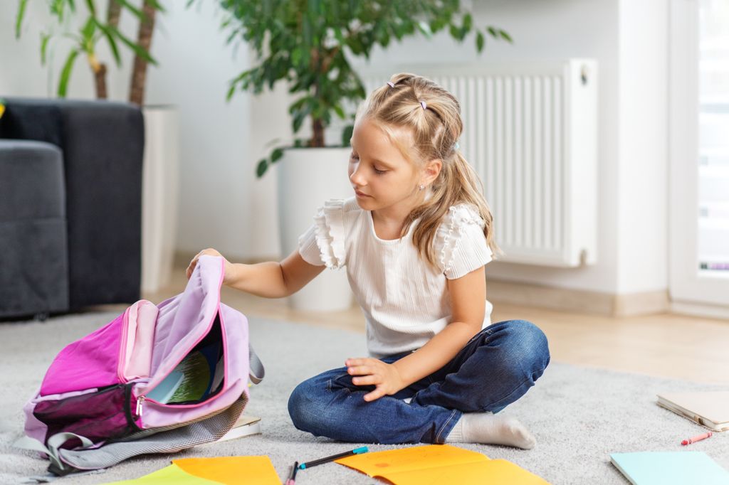 Niña organizando su mochila escolar en su casa