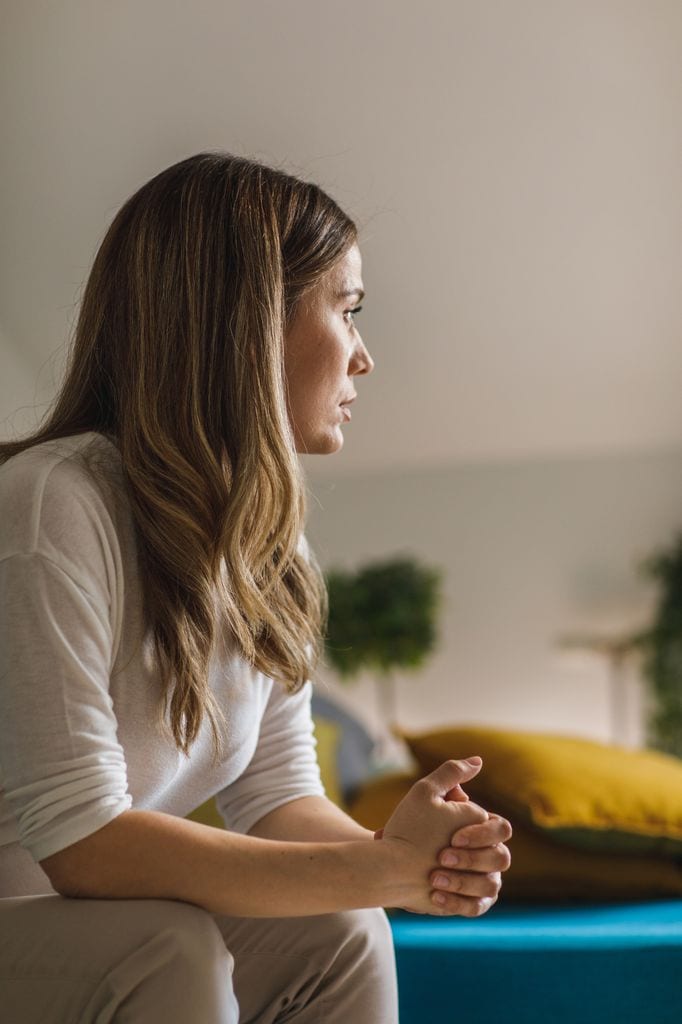 Una mujer nerviosa en el sofá mirando al horizonte pensativa