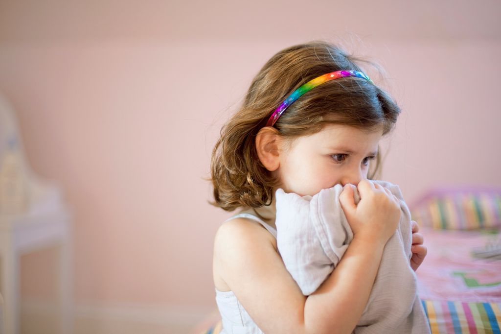 niña pequeña agarrada a una mantita, con miedo