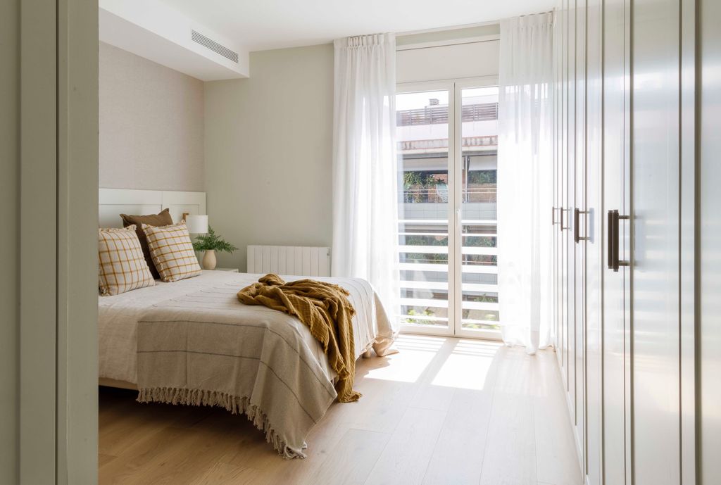 Dormitorio con mucha riqueza en los textiles, que visten la cama y la ventana