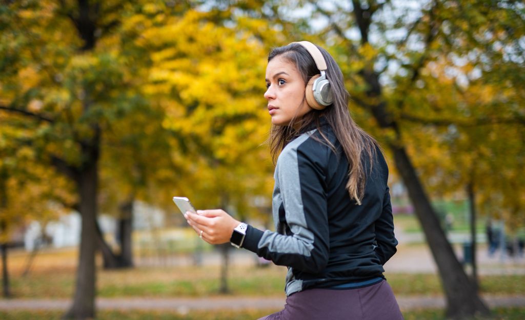mujer seria sola haciendo deporte en el parque, con el móvil en la mano