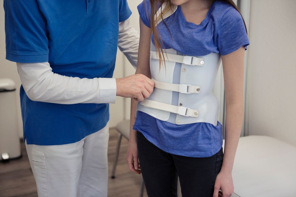 niña en el médico con un corsé corrector para la escoliosis