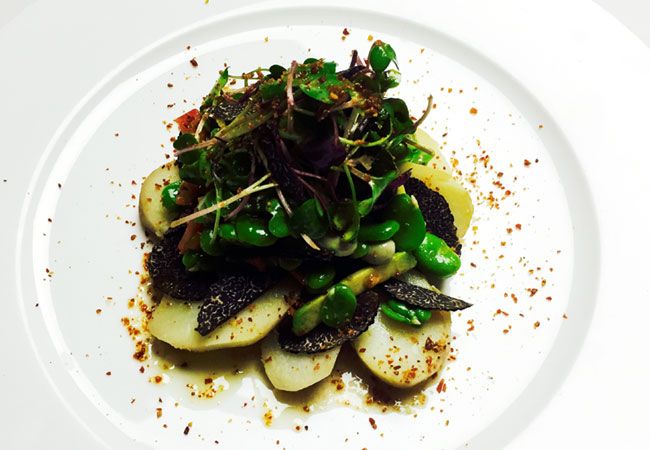 Ensalada de habas frescas, brotes verdes, patata asada y trufa negra. Uno de los platos del menú homenaje a la trufa del restaurante 'Aldaba', en Madrid.

