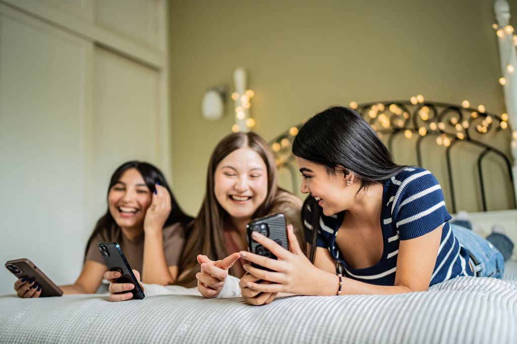 chicas adolescentes sonrientes usando su móvil