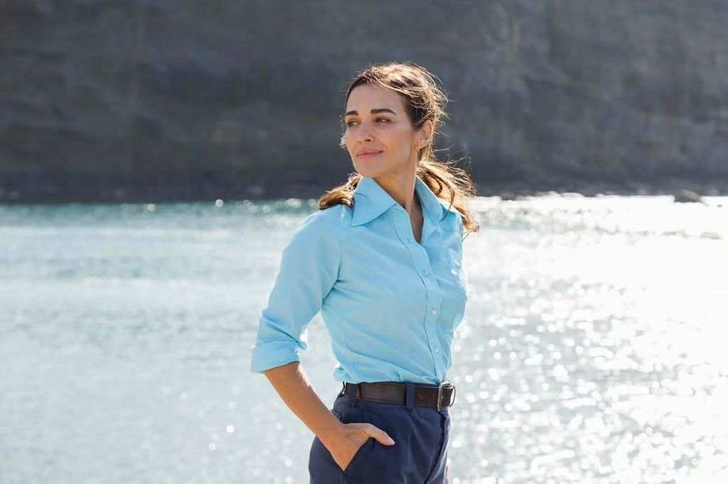 Paula Echevarría sonríe junto al puerto con un vestido azul estampado y la melena suelta peinada con raya lateral