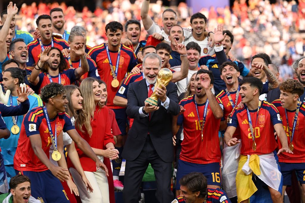 El Rey alzando la copa, rodeado de los campeones del mundo, la reina Letizia y sus dos hijas