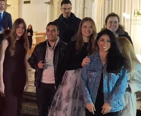 Plano medio de la Princesa Leonor e infanta Sofía haciéndose una foto con un grupo de fans en a la salida del Hotel Reconquista