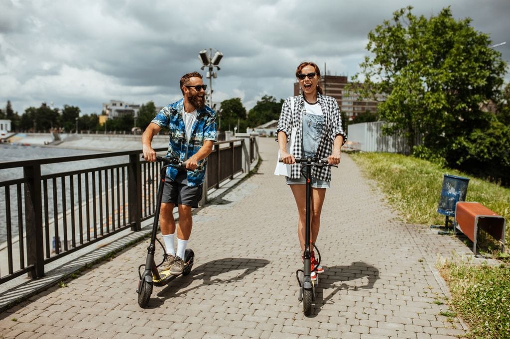 Una pareja disfruta circulando en patinete eléctrico por la ciudad