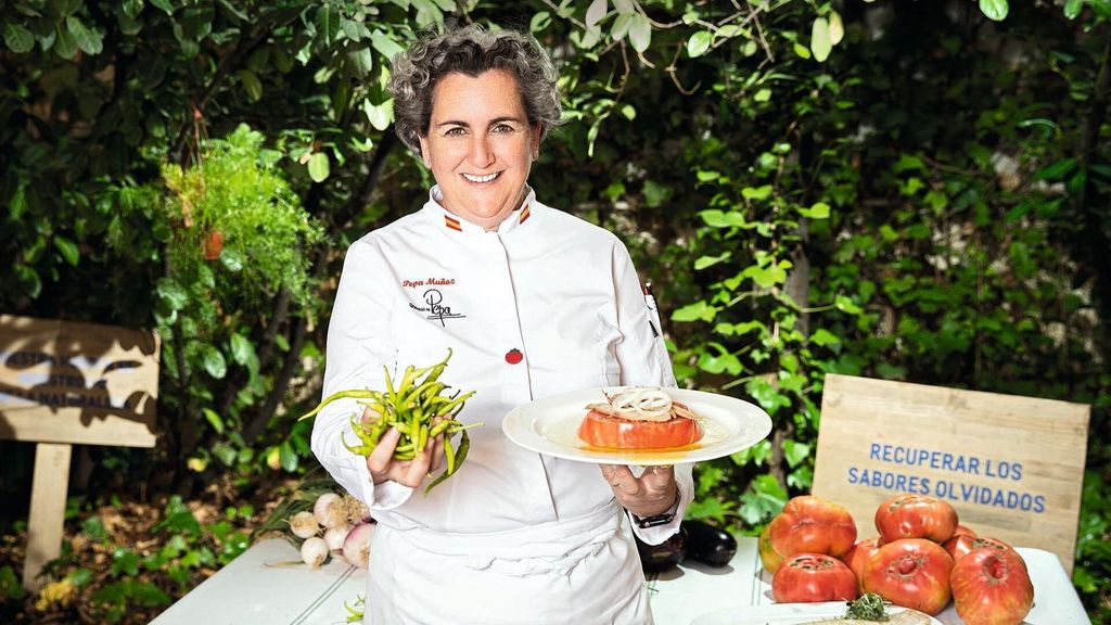 Pepa Muñoz con un plato de tomate en una mano y piparras frescas en la otra.