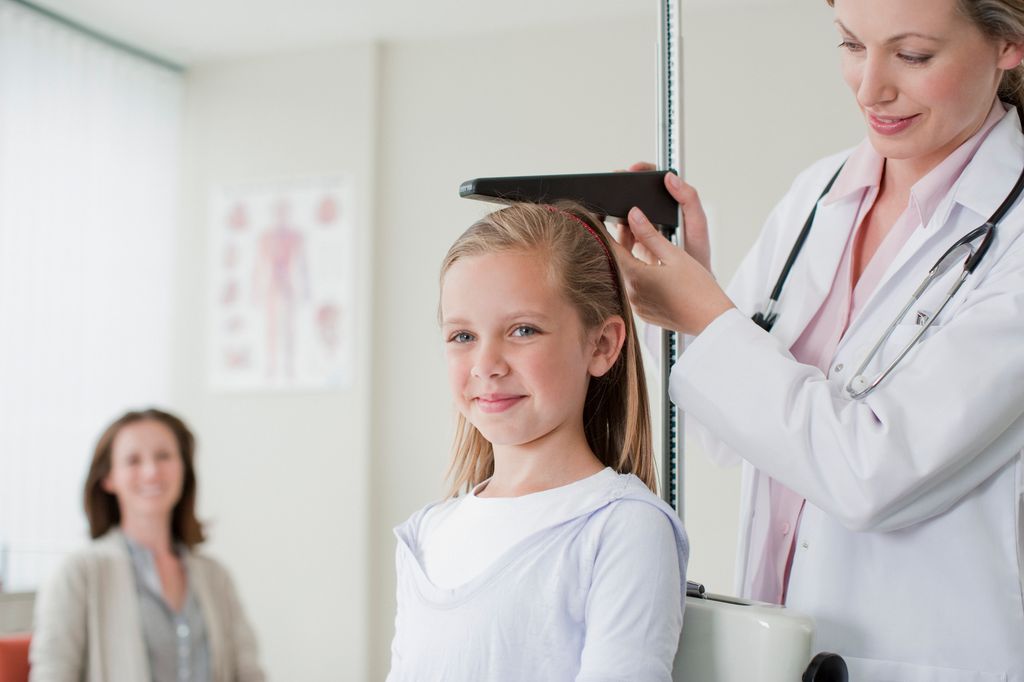 Pediatra mide la talla de una niña en consulta