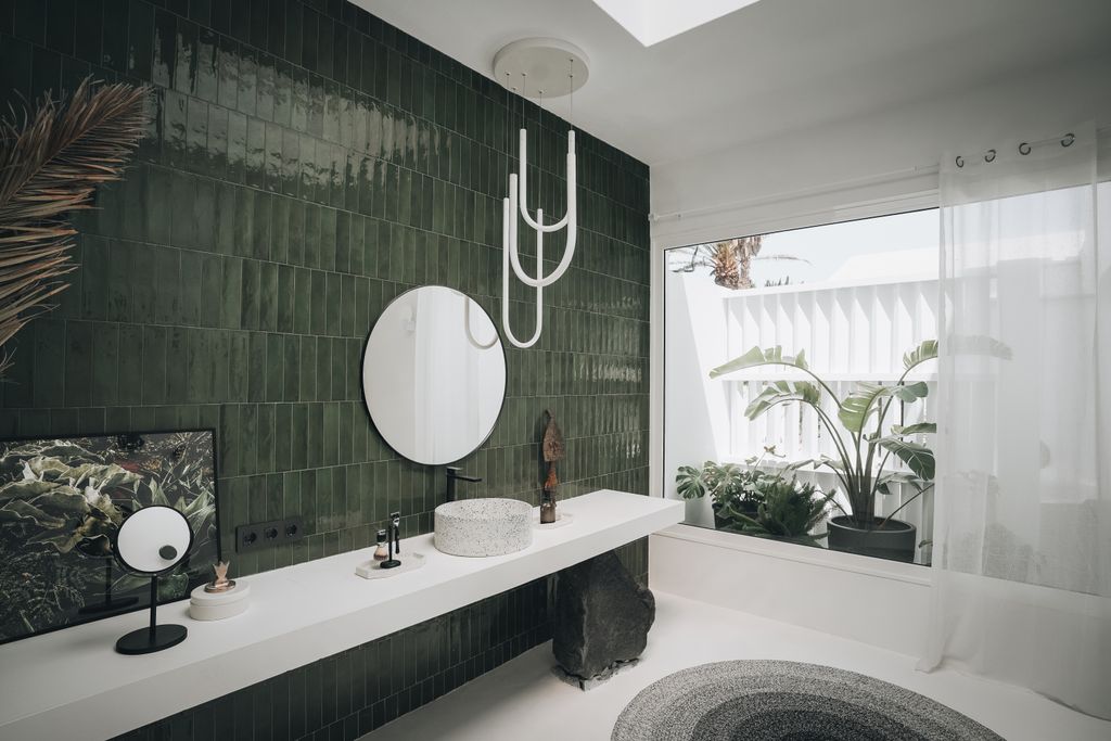 Una piedra volcánica, una pared cerámica en verde y el blanco dominante, en un baño moderno