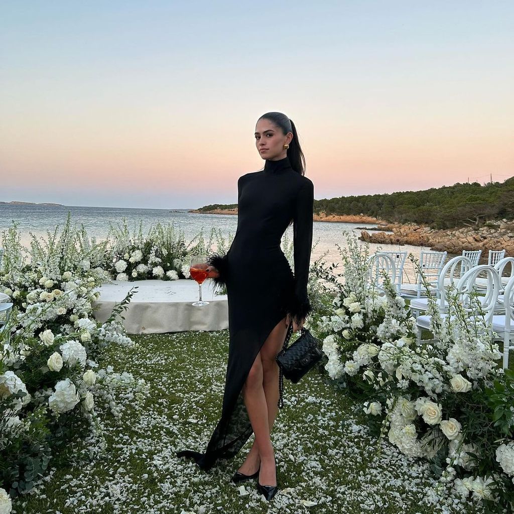 Plano entero de Kim Turnbull en un evento en la playa con vestido asimétrico negro