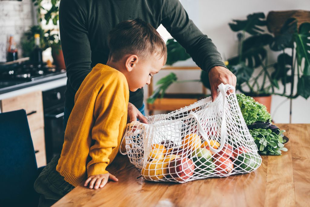 Padre con su hijo deshaciendo la cesta de la compra vegana
