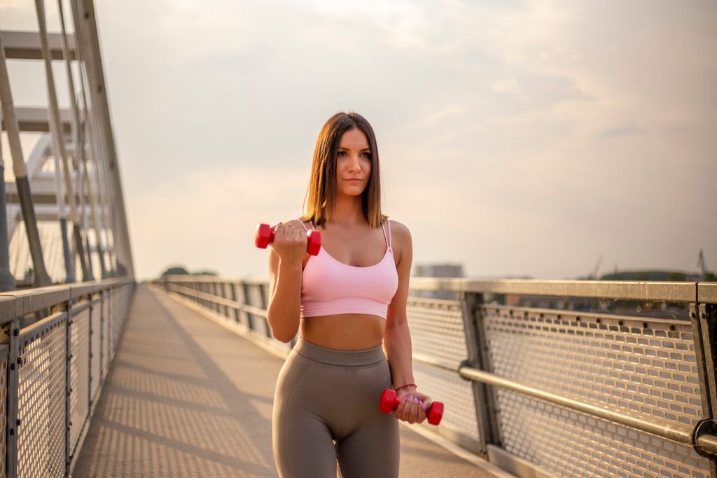 mujer caminando con pesas al aire libre