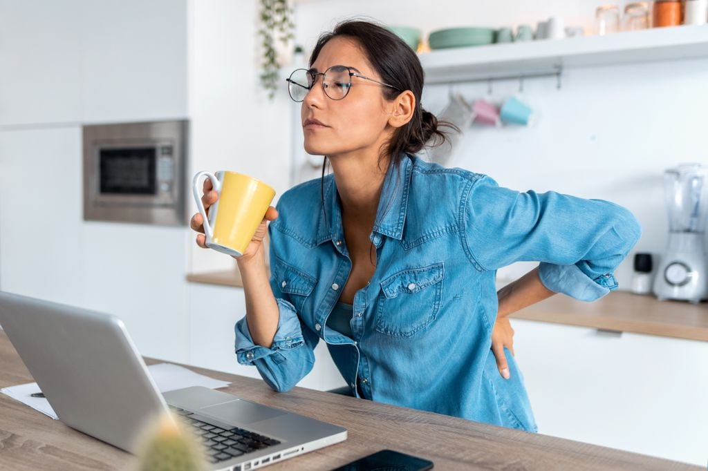 mujer tomando un café, seria, con dolor de espalda