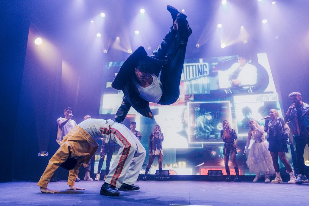 Plano medio de una actuación del MecanExperience de bailarines haciendo saltos