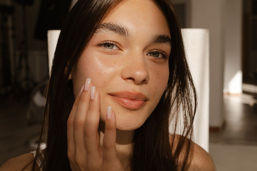 Adolescente poniéndose crema en la cara