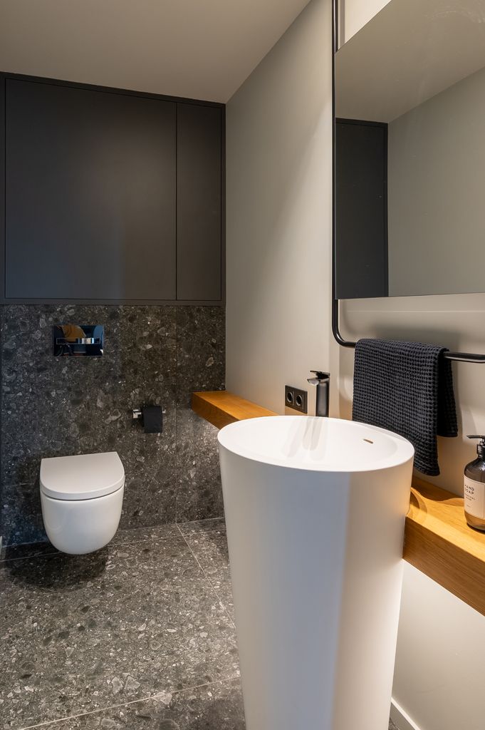 Baño con inodoro con cisterna empotrada y armario empotrado encima.