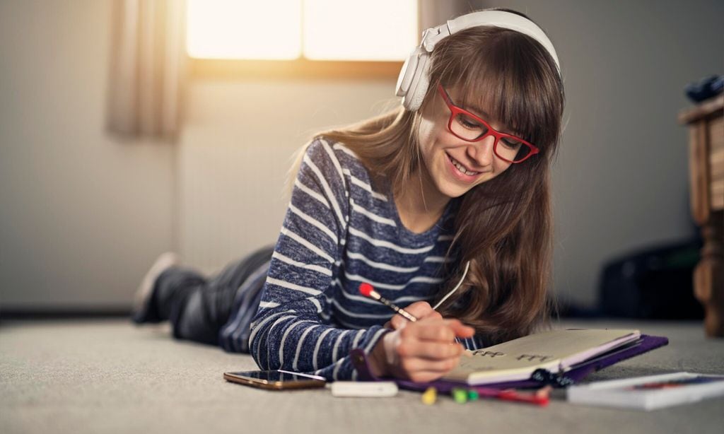teenage girl writing diary and talking on the phone