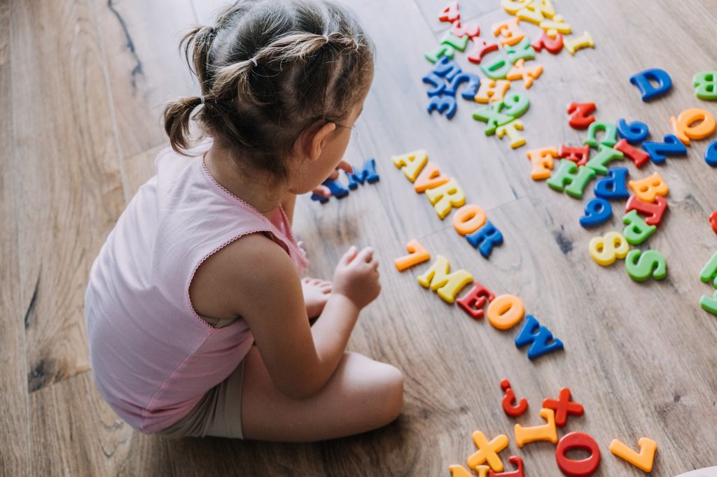 Niña pequeña jugando con letras magnéticas