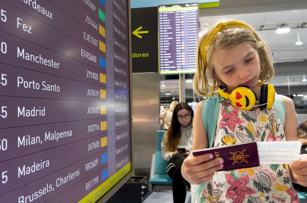 Niña viendo su pasaporte en un aeropuerto