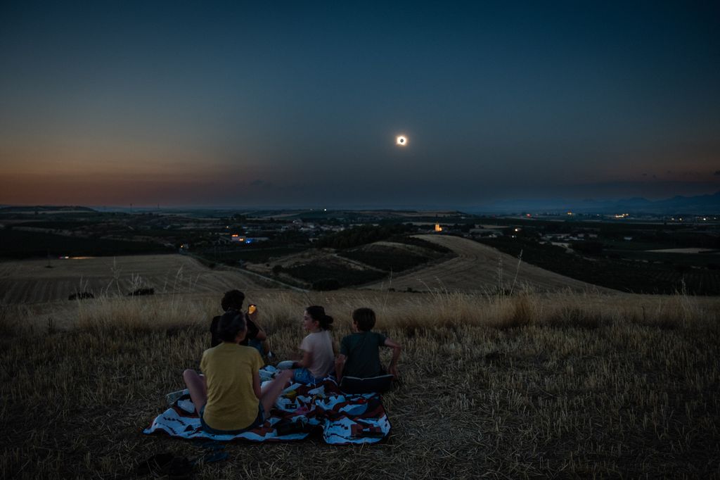 Sentados sobre una manta en mitad del campo, una familia contempla la totalidad desde Gimileo, en La Rioja, poco antes de la puesta de sol.