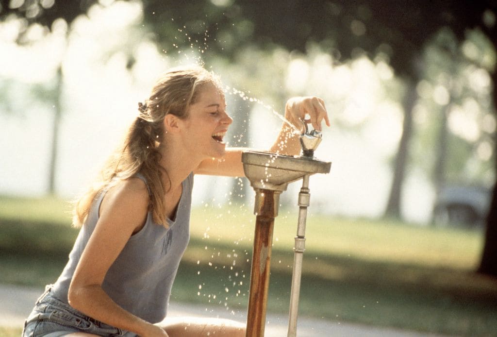 mujer refrescándose del calor en una fuente