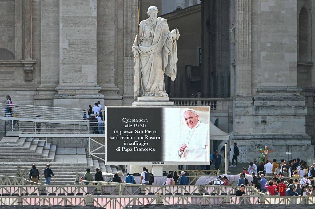 Esta foto muestra una pantalla gigante invitando a los fieles al rosario por la memoria del Papa Francisco, en la Plaza de San Pedro.  