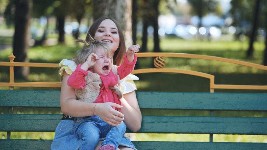 Madre conteniendo una rabieta de su hija en un parque