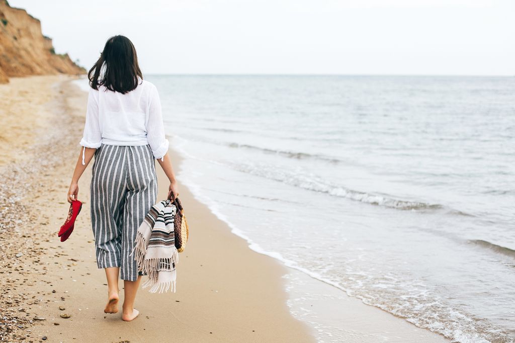 mujer caminando descalza por la playa