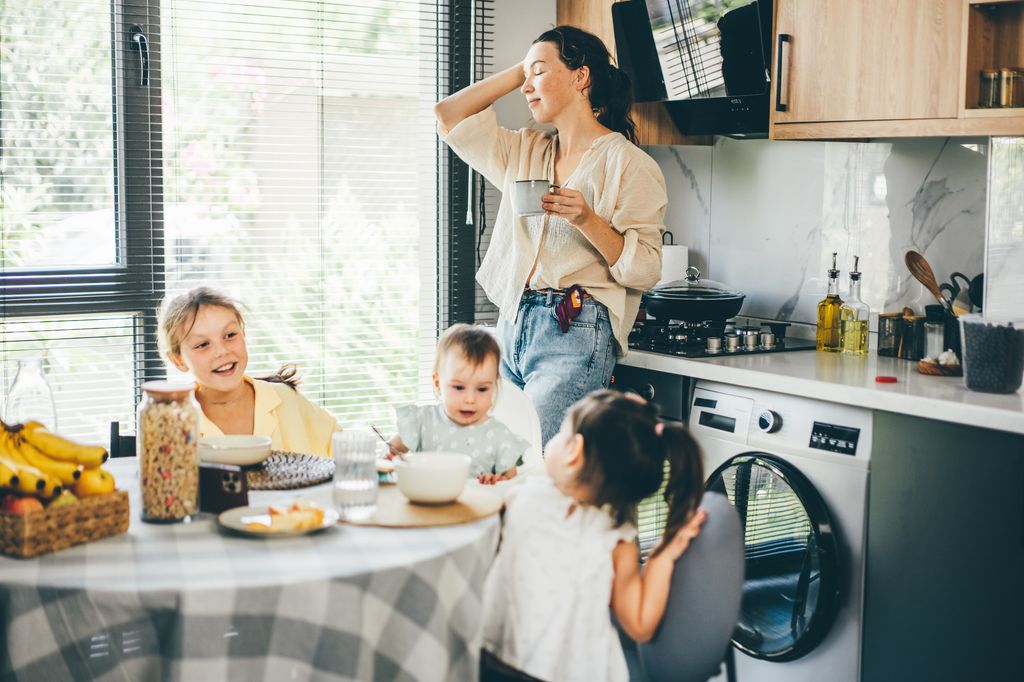 madre cansada en la cocina, junto con sus tres hijos pequeños