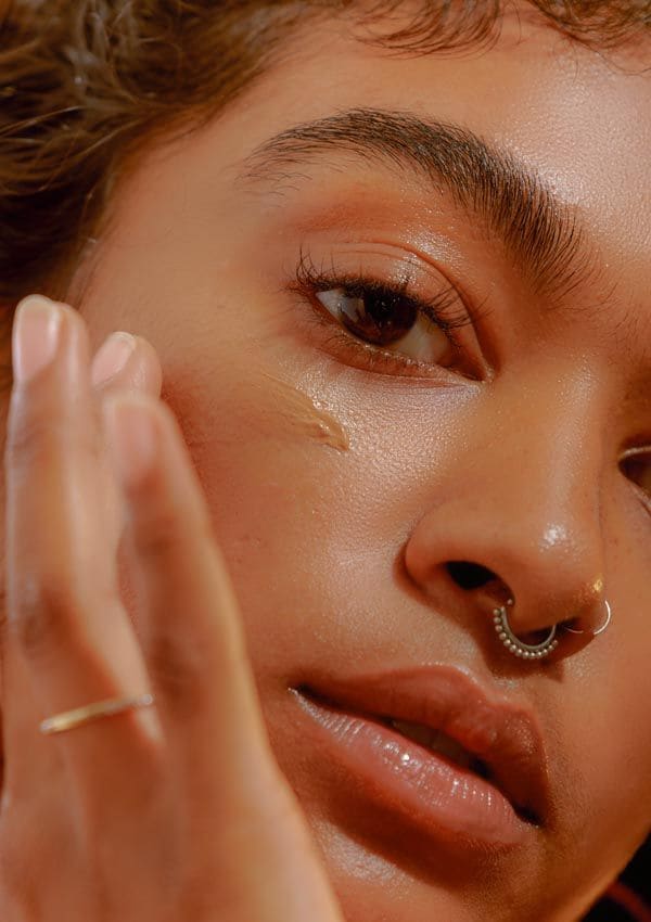 Mujer morena aplicando crema en el rostro