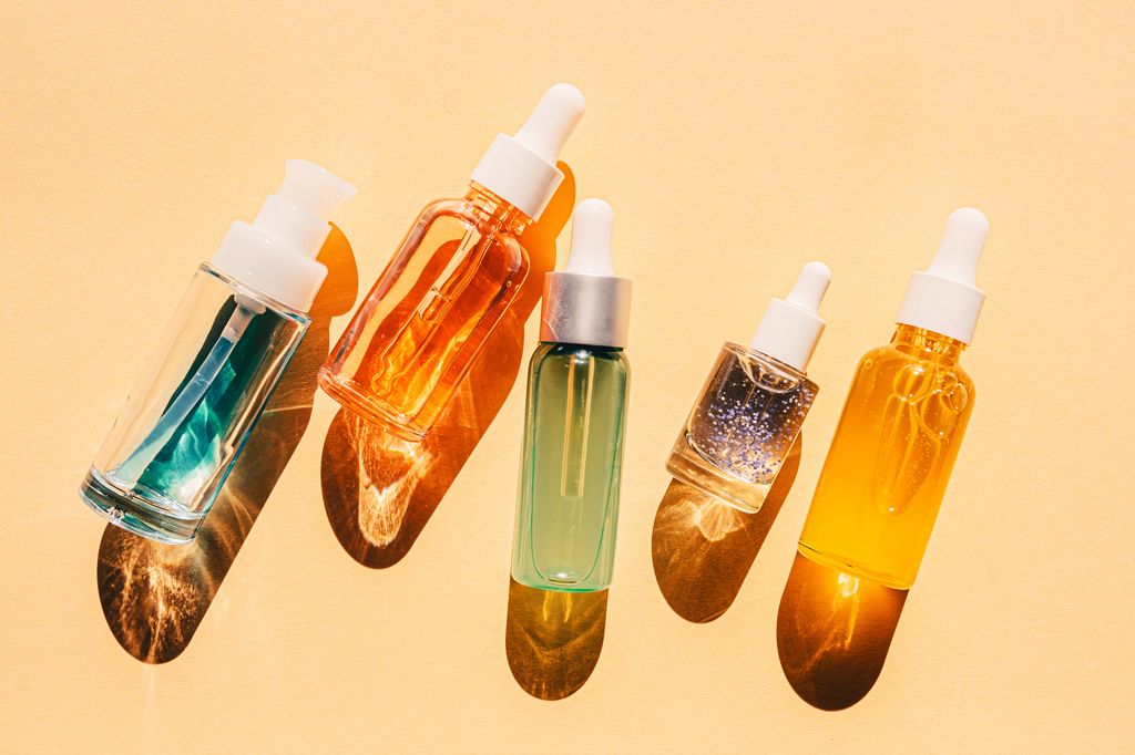 Assorted glass bottles with cosmetic liquids, serum or gel. Vibrant trendy background of  cosmetic products, flat lay style