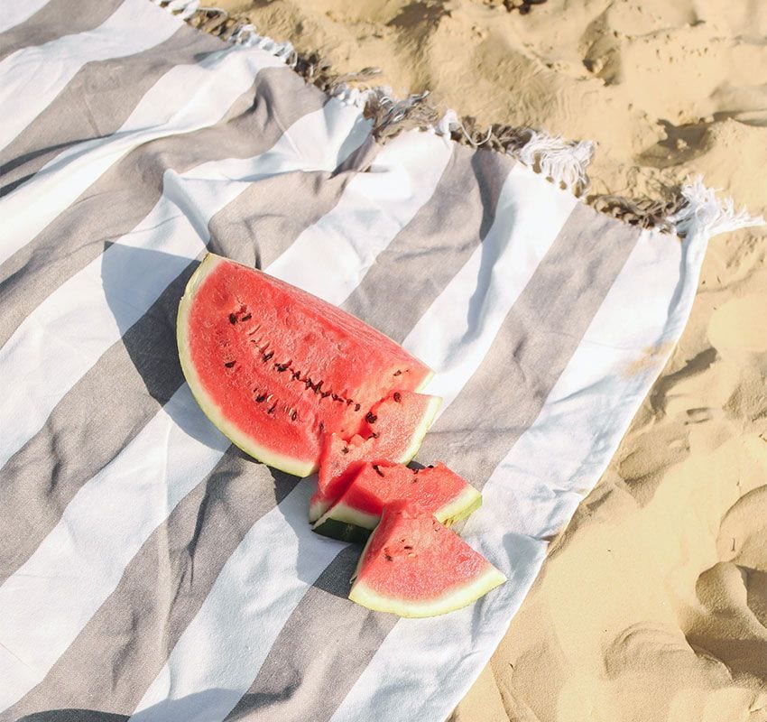 Media sandía en una toalla sobre la arena de la playa